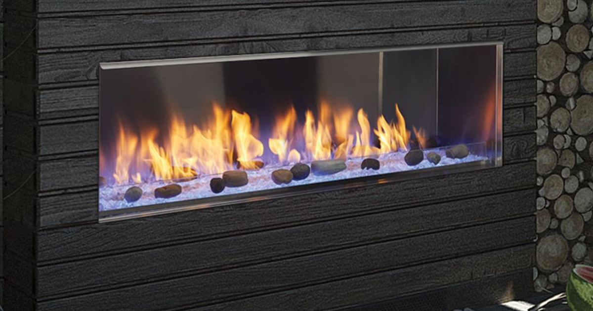 A Majestic Lanai outdoor linear gas fireplace burning on a dark patio wall